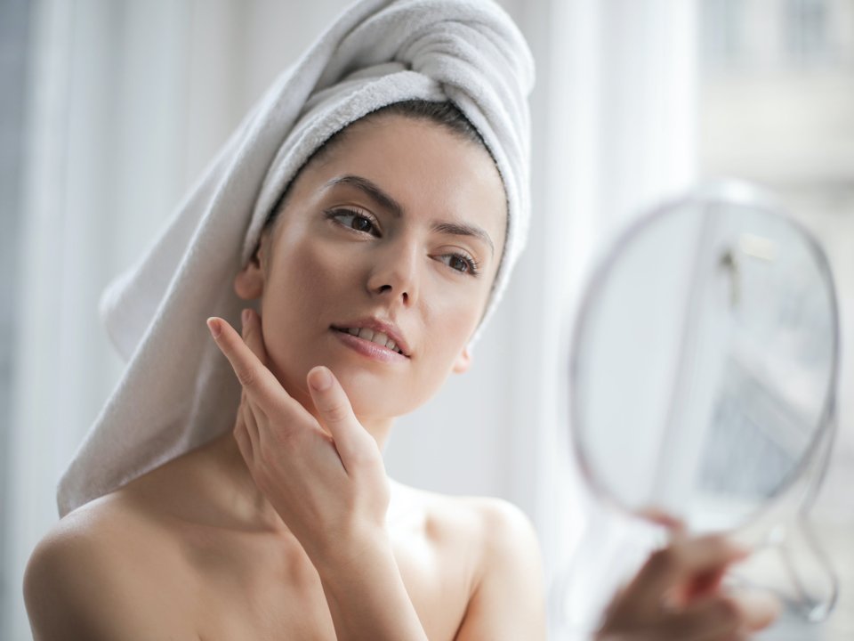 Woman inspecting her clear skin after getting spa facial treatment
